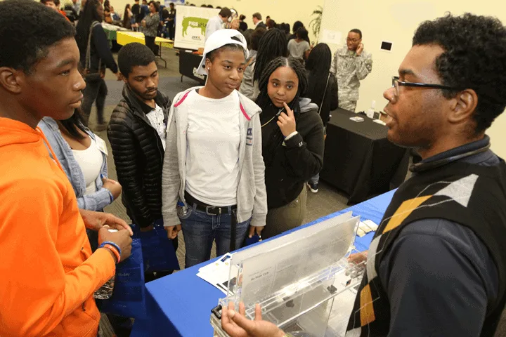 Students engaging with a STEM demonstration at a science fair.