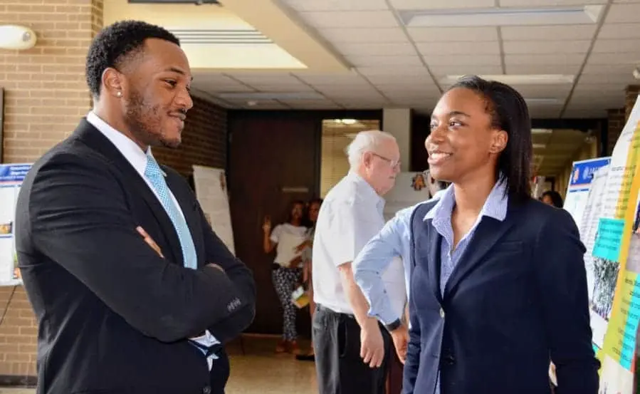 A woman and a man engaging in conversation at a professional event or conference.
