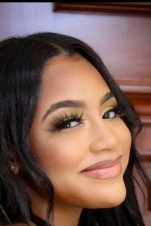 Portrait of Kyra Pierce with long dark hair and thick eyelashes smiling sideways