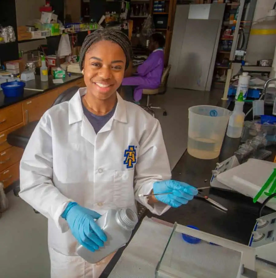 Young female scientist working in a laboratory with lab equipment and chemicals.