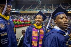 Graduates celebrating at a university graduation ceremony in caps and gowns.