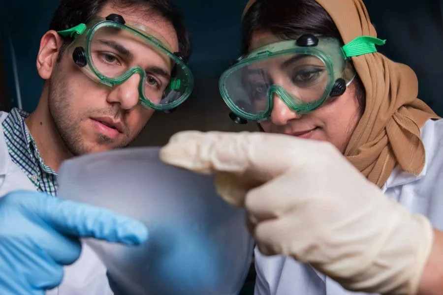 A scientist and a researcher examining a sample with laboratory tools.