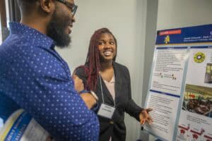 Innovative research presentation at academic conference with diverse students and poster display.