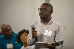 Engaged man speaking at conference with audience members listening attentively.