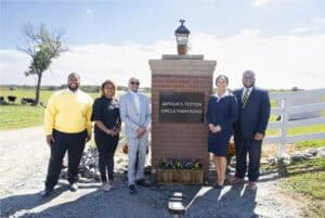 Group of professionals standing outdoors near a brick sign at Circle Farm Road.