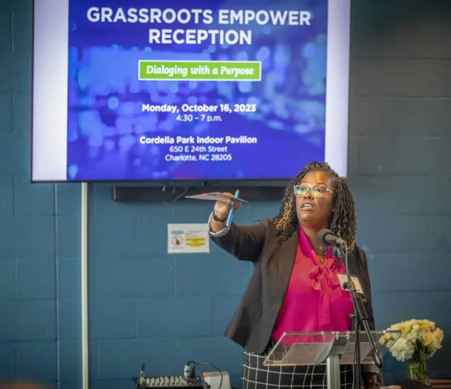 Empowering community leaders at grassroots reception with speaker presenting at podium.