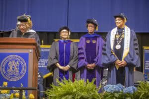 Graduation ceremony with diverse graduates in academic regalia at CAES News event.