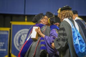 Graduates celebrating at a university commencement ceremony, wearing caps and gowns.