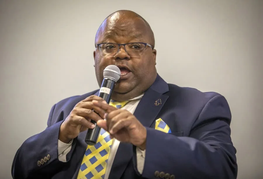 A man speaking into a microphone at a conference or event.