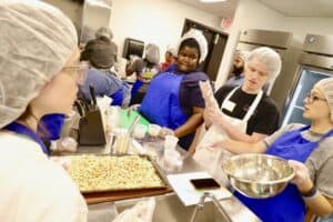 Healthy food preparation class with diverse students in a commercial kitchen setting.
