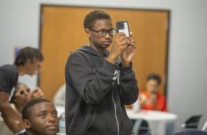 Taking a photo with a smartphone in a classroom setting.