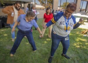 People dancing and enjoying a lively outdoor event, engaging with each other in a joyful atmosphere.