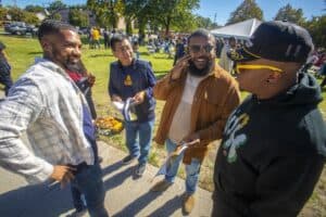 Four friends engage in conversation outdoors, sharing food and laughs at a lively community event.