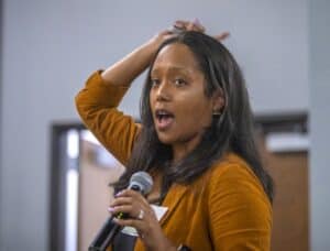 Woman speaking into a microphone at a conference or seminar.