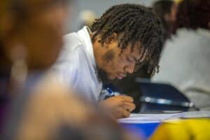 Focused student taking notes during class, emphasizing education and learning environment.