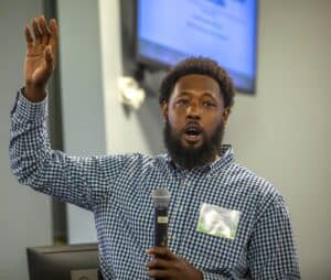 Elevated hand gesture during presentation at a conference or seminar.