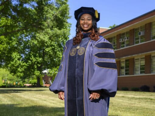 Graduation woman in academic gown outdoors at university campus.