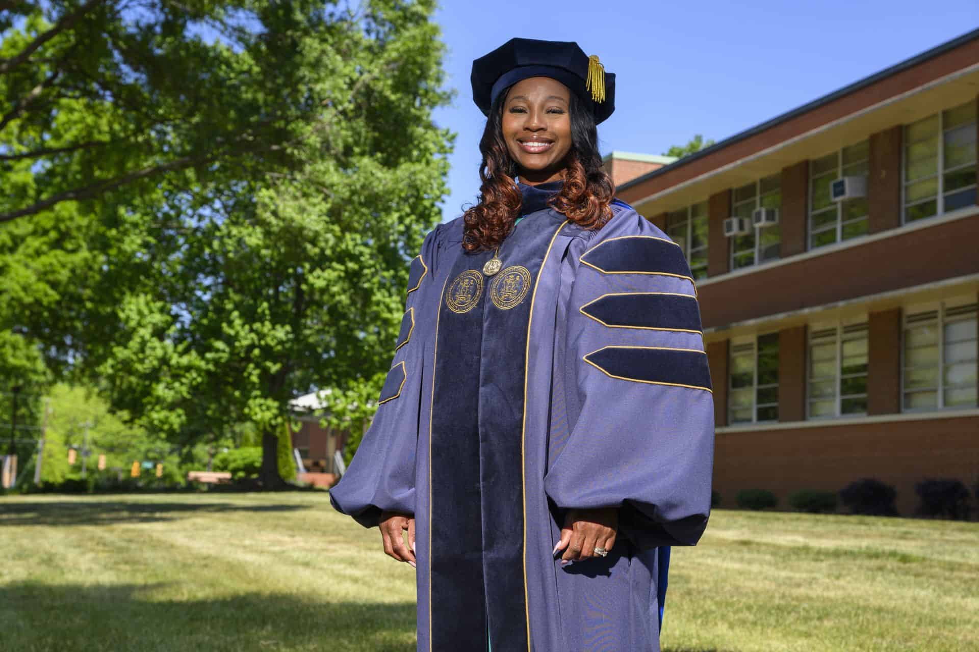 Graduation woman in academic gown outdoors at university campus.