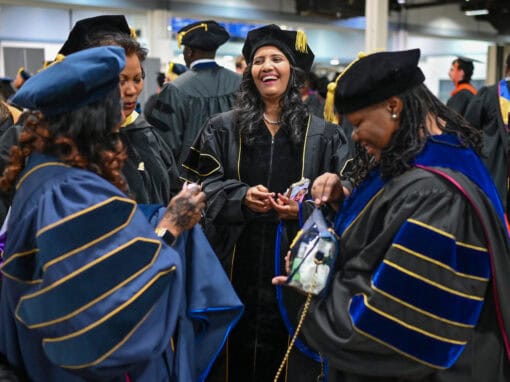 Graduates celebrating at a university commencement ceremony in academic regalia.