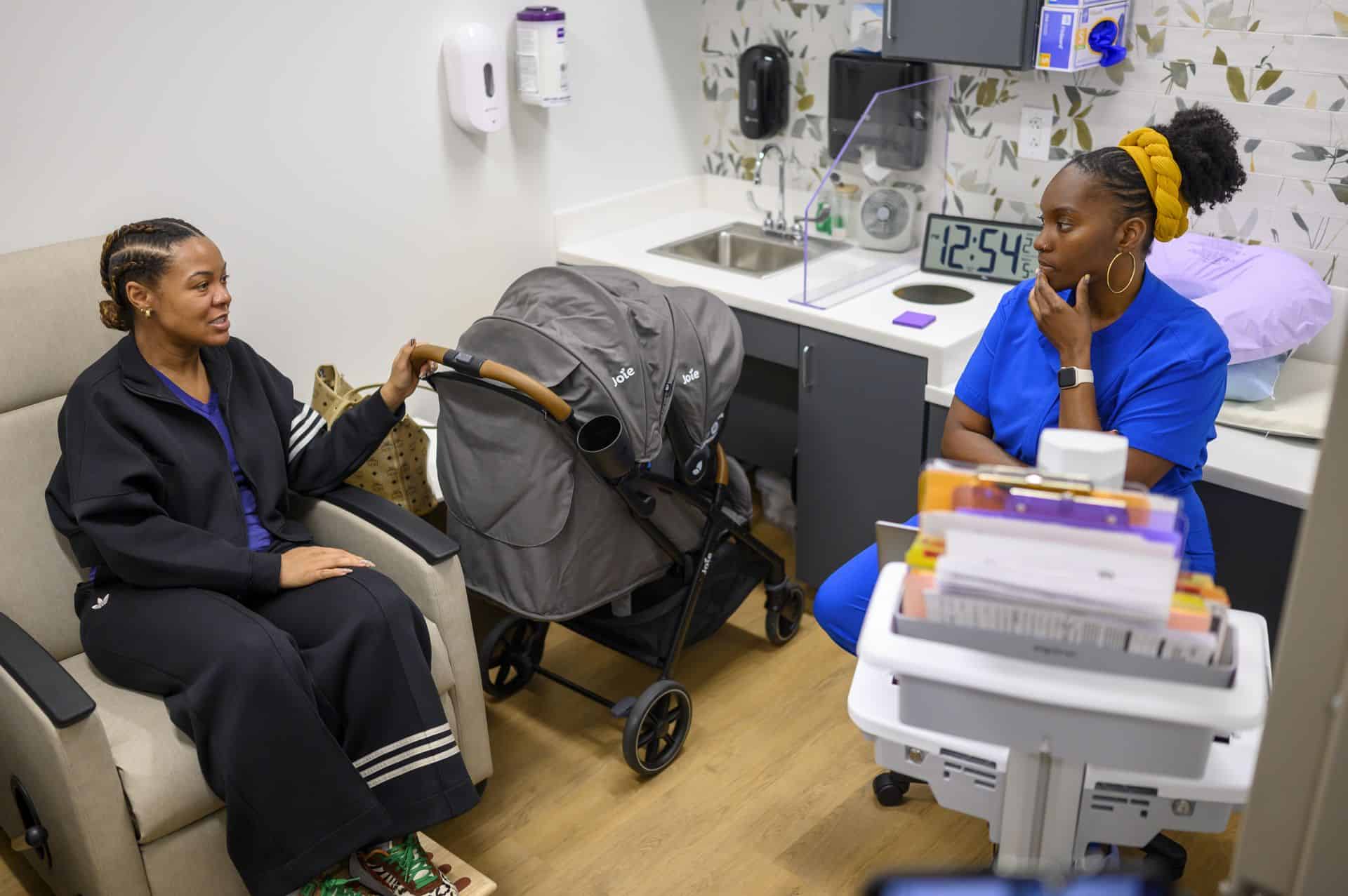 Doctor consulting with a patient in a medical office with a stroller nearby.