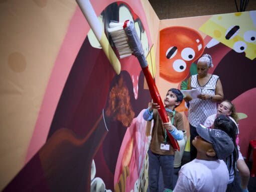 Children and adult painting a colorful mural at an art event.