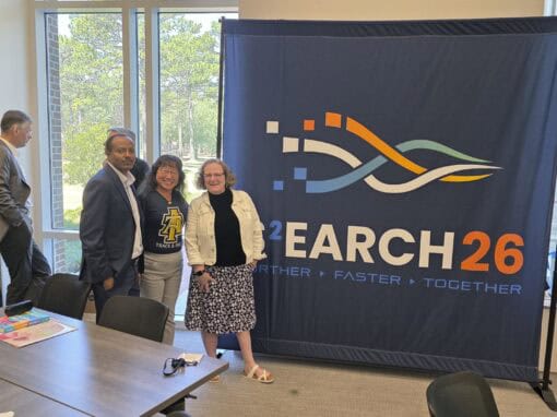 Group of professionals at CAES News event with banner in background.