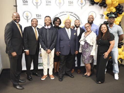 Group of diverse professionals at CAES News event with university branding.