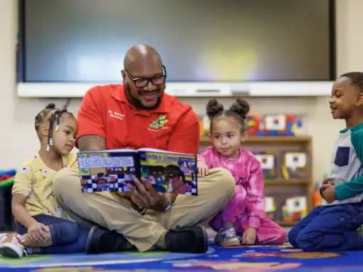 Teacher reading a book to young children in a classroom setting.