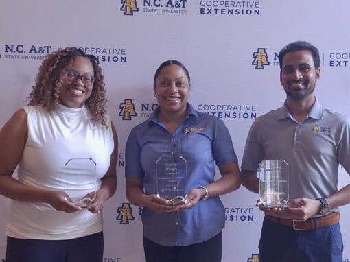 Group of three people holding awards at CAES News event.