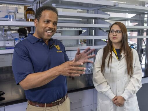 Scientists discussing in a laboratory with scientific equipment and shelves.