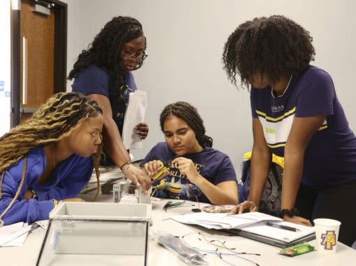Group of young women working together on a science project in a classroom.