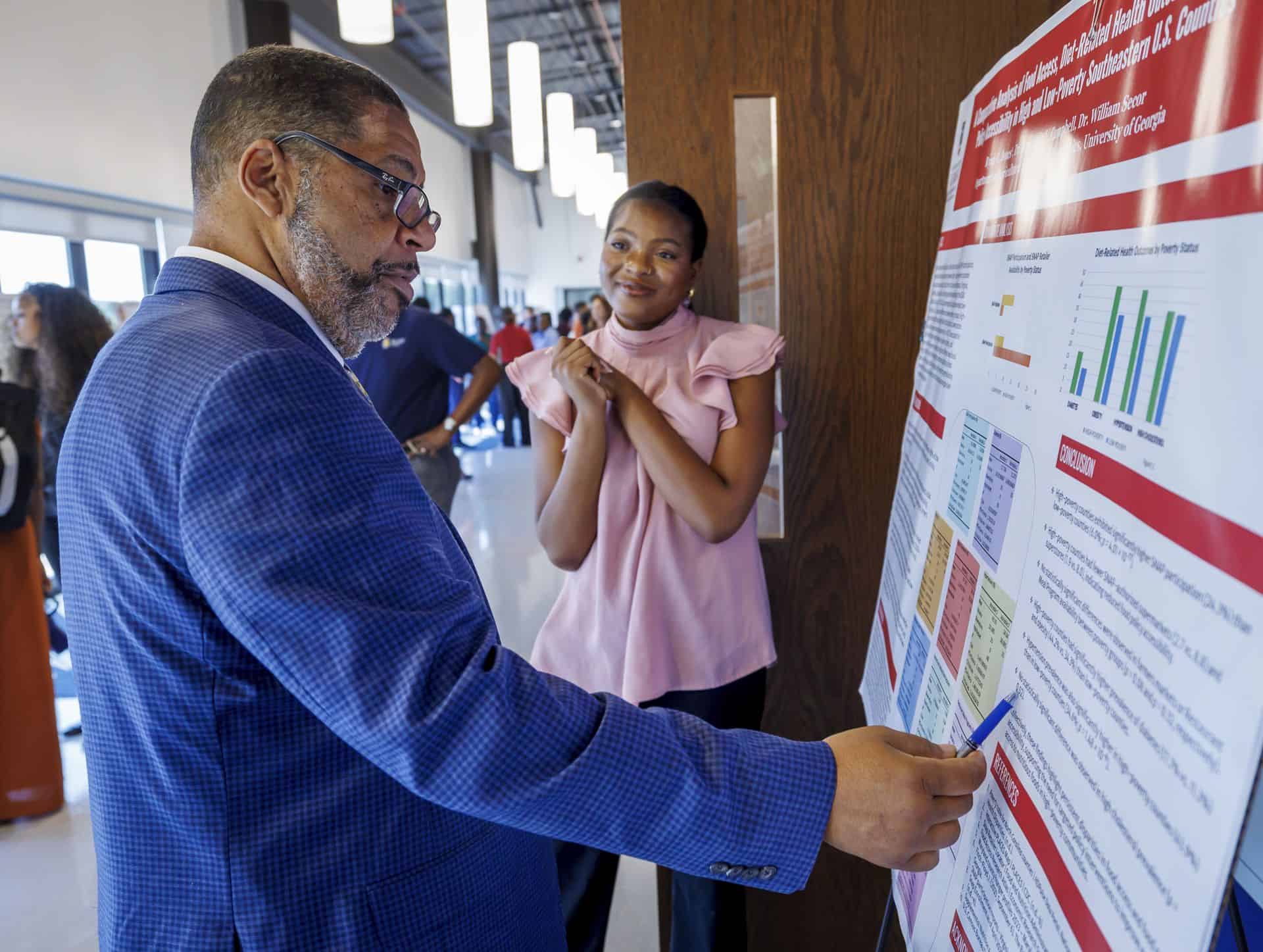 Business professional presenting research data at conference poster session.