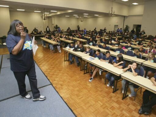 Speaker addressing a large group of students in a spacious hall.