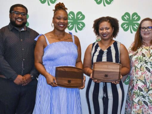 Group of four diverse women and man at CAES News event holding wooden boxes.