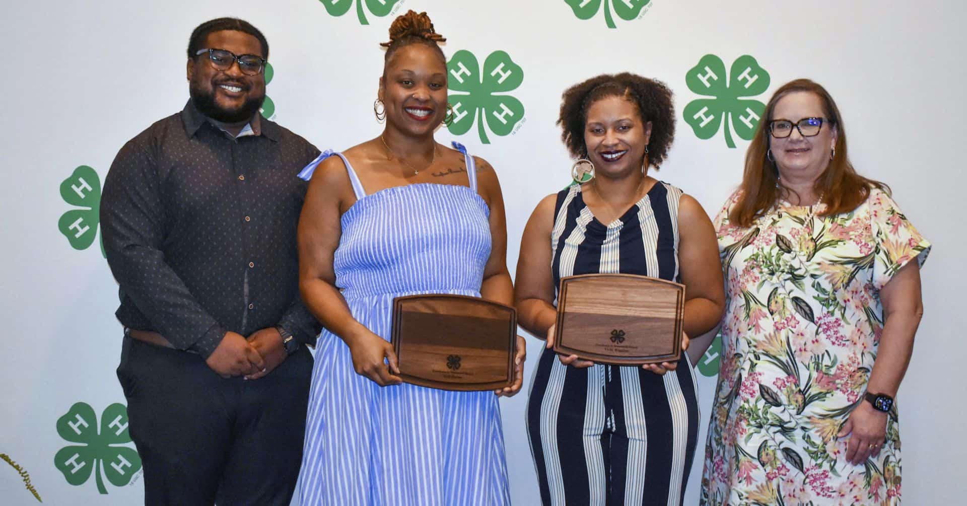 Group of four diverse women and man at CAES News event holding wooden boxes.