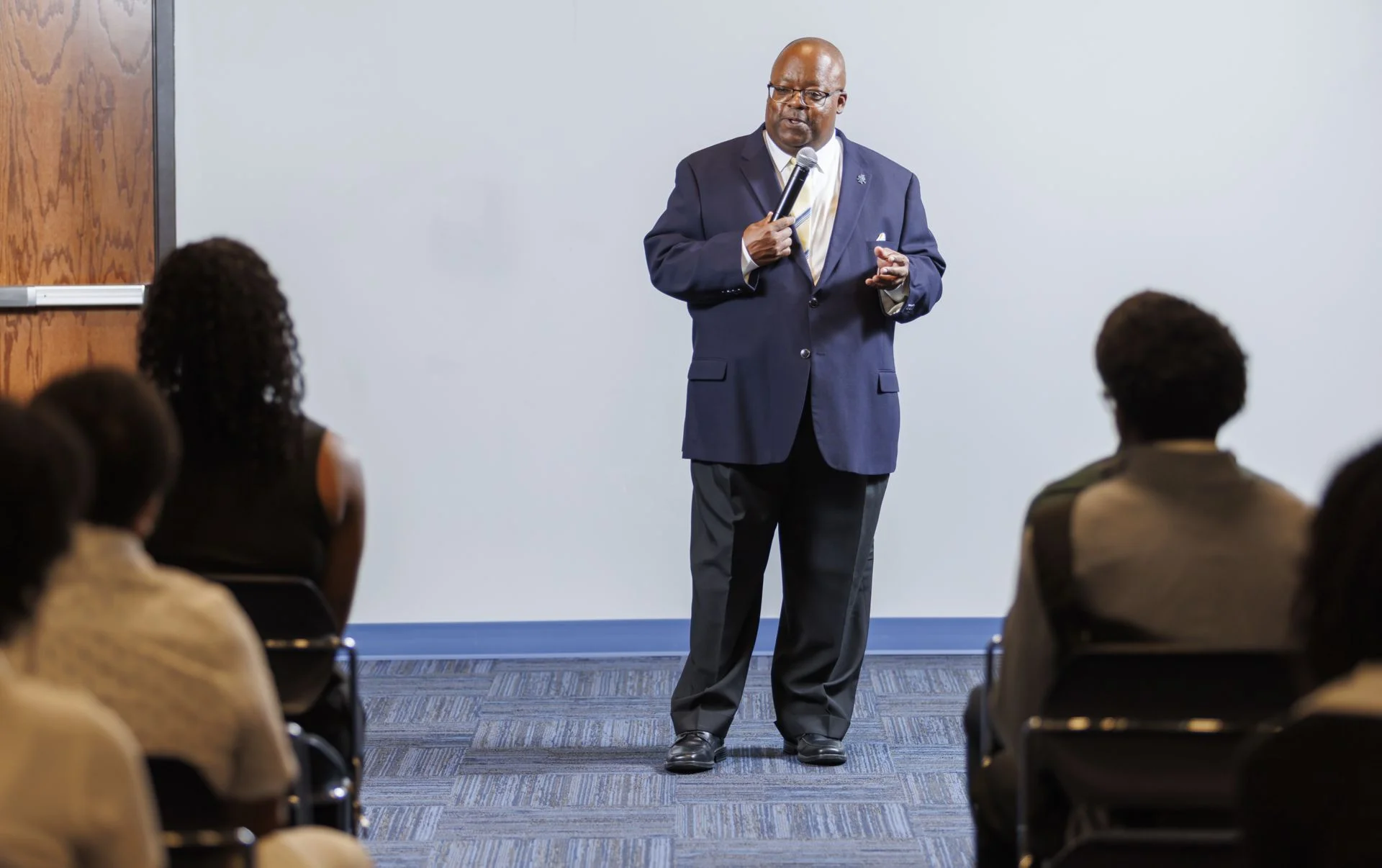 Antoine Alston speaks into a microphone before a seated audience at the CAES Student Showcase of Excellence.