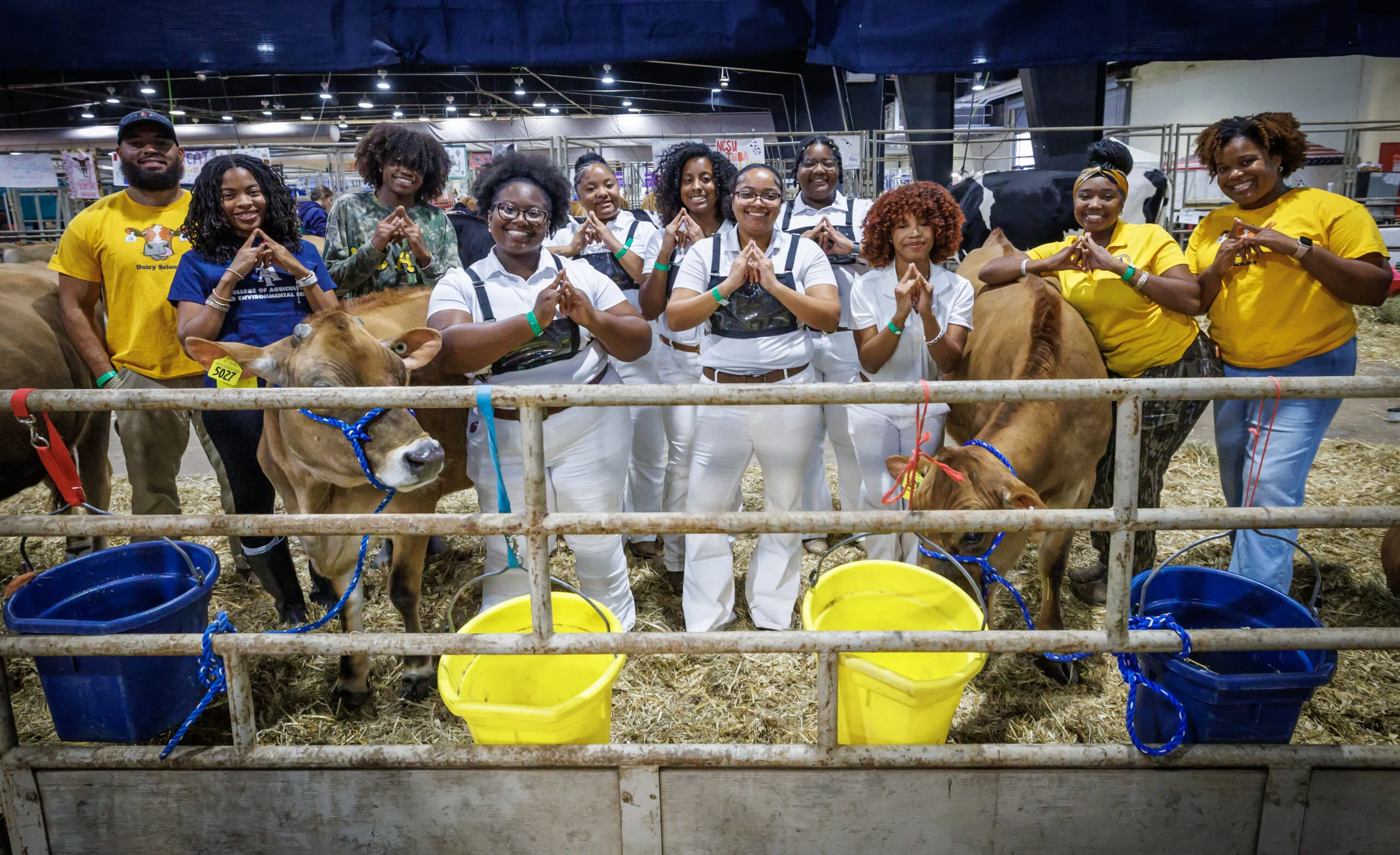 Group of dairy cattle team members posing with cows at a fair.